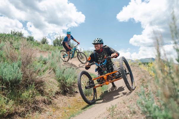 An adaptive mountain biker rides on a wide trail in Round Valley in Park City, UT