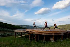 Three women do yoga on a yurt pad at Bluesky near Park City, UT