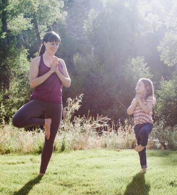 Woman and child in a yoga pose on the grass