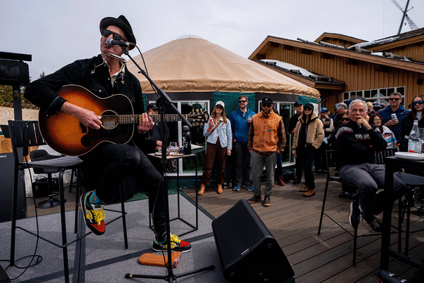 A musician sings and plays guitar on a patio outside of Chute 11 at Deer Valley in Park City, UT