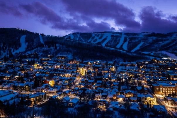 Park City, UT streets lit up at dusk below ski runs and a purple sky