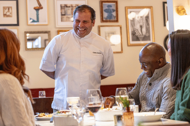 A chef laughs and talks with patrons at a restaurant in Park City, UT