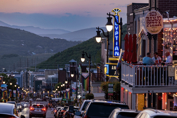 Patrons eat on a restaurant deck overlooking Main Street, Park City, UT at dusk.