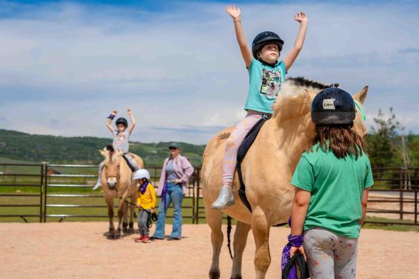 A young girl rides a therapy horse with her arms closed at the NAC Ranch near Park City, UT