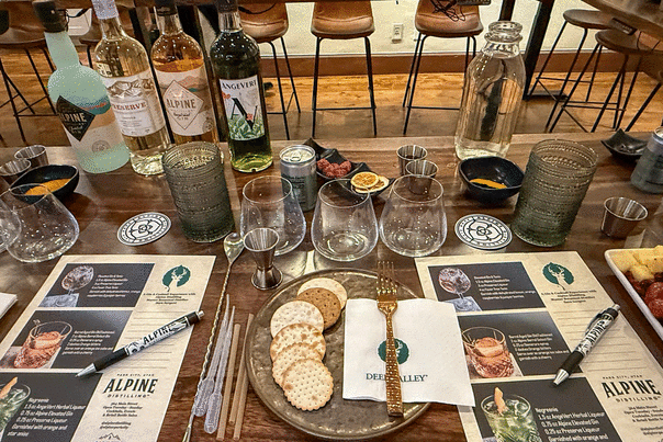 A spread of cocktail making supplies and snacks set on a wood table at the Deer Valley Academy in Park City, UT