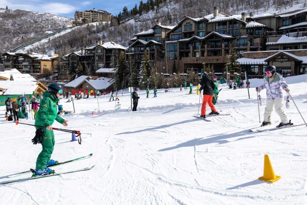 An ski instructor gives lessons to beginner skiers on a sunny day at Deer Valley in Park City, UT
