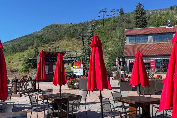 Silver Star Cafe patio with lowered red umbrellas and the Silver Star chairlift on a sunny day