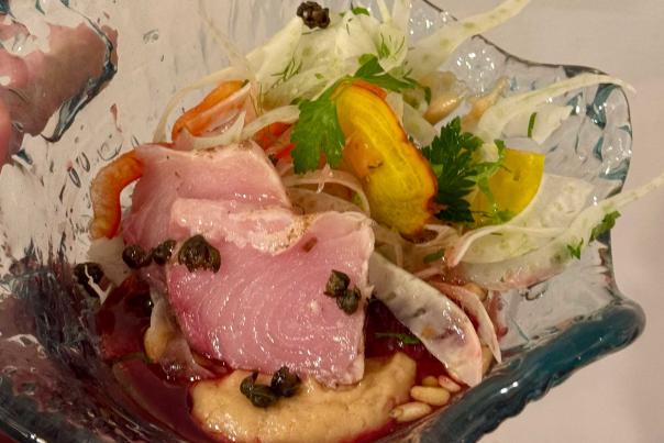 A plate of  food rests in a glass dish held by a hand in Red Flower Studios in Park City, UT