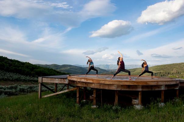 Three women do yoga on a yurt pad at Bluesky near Park City, UT
