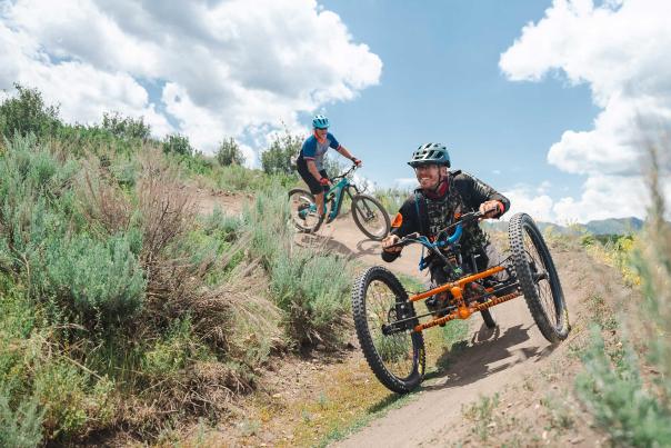An adaptive mountain biker rides on a wide trail in Round Valley in Park City, UT
