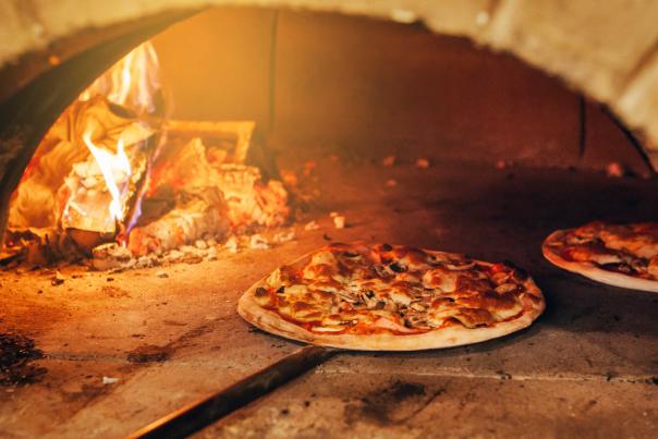 A pizza is slid into a wood-fired oven for baking at a pizza restaurant in Park City, UT