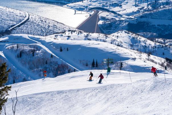 Three skiers descend Stein's Way on a bluebird day in Park City, UT