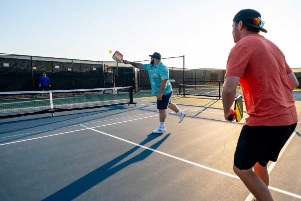 Three people play pickleball at sunset on a court in Park City, UT