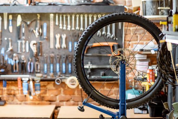 A mountain bike wheel sits in a truing stand in front of bike tools hanging on a wall in a bike shop in Park City, UT