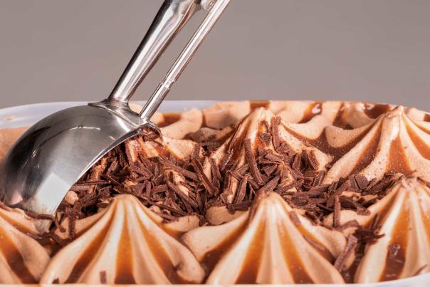 An spoon scooping out chocolate ice cream with flakes on top in an ice cream shop in Park City, UT