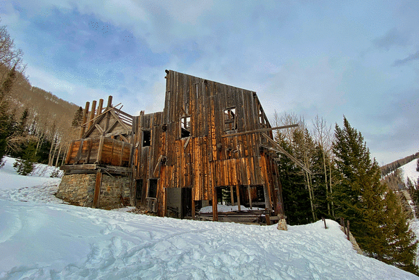 A view of an old mining structure surrounded by snow on a sunny day at Park City Mountain