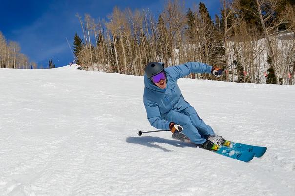 A skier smiles at the camera as he carves a turn on a groomed run at Park City Mountain