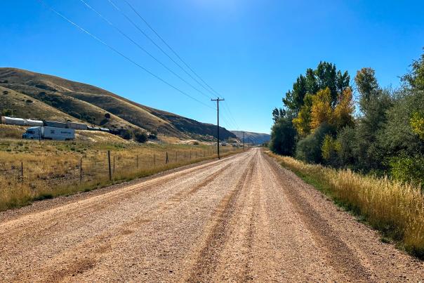 A gravel road with ranch land and trees on either side near Park City, UT