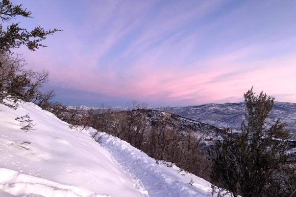 A colorful sky and snowy trail during sunrise in winter