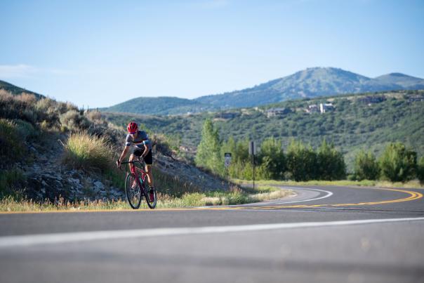 Road biker on curve with mountains in background