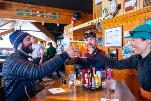 Three people cheers beer glasses at the Sticky Wicket apres ski bar in Park City, UT