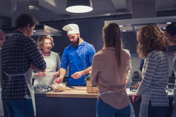 A group of people watch a chef explain how to prepare a meal in a restaurant in Park City, UT