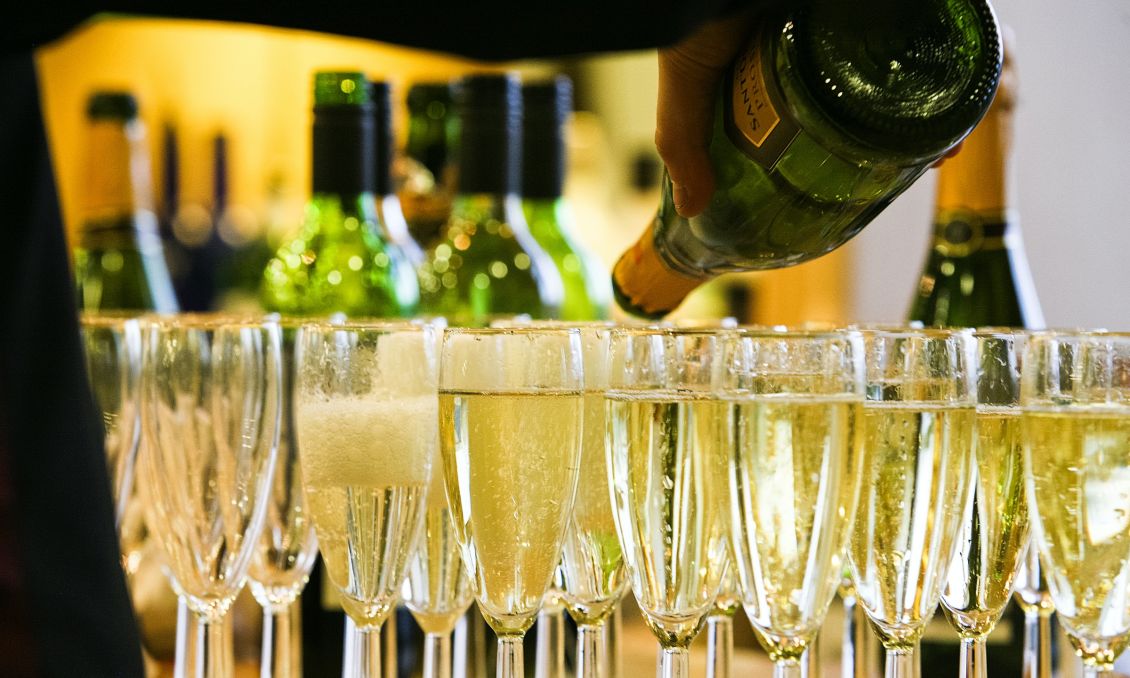 a dozen champagne glasses being filled by person holding bottle