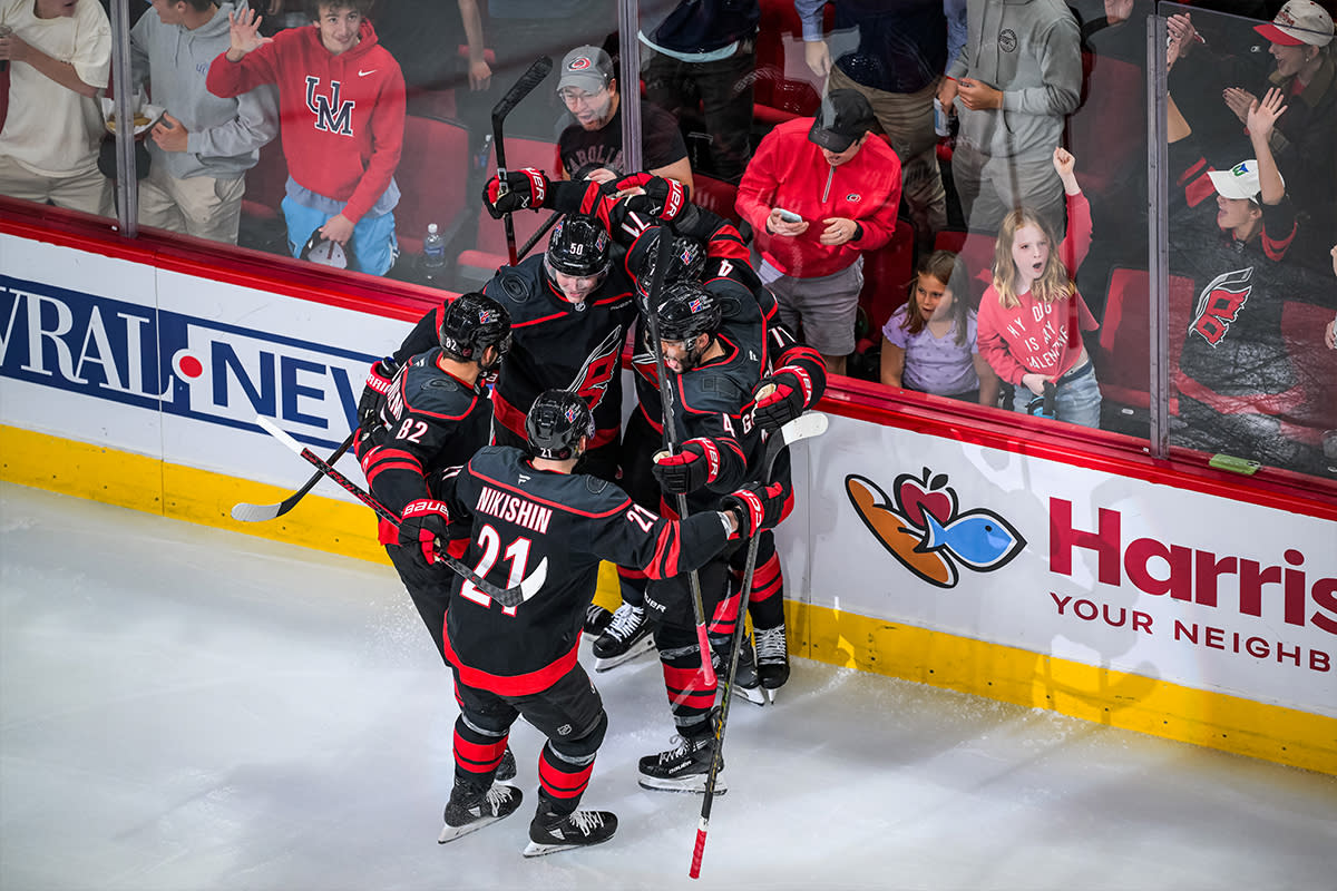 Carolina Hurricanes players huddle to celebrate scoring a goal at Lenovo Center in Raleigh, N.C.