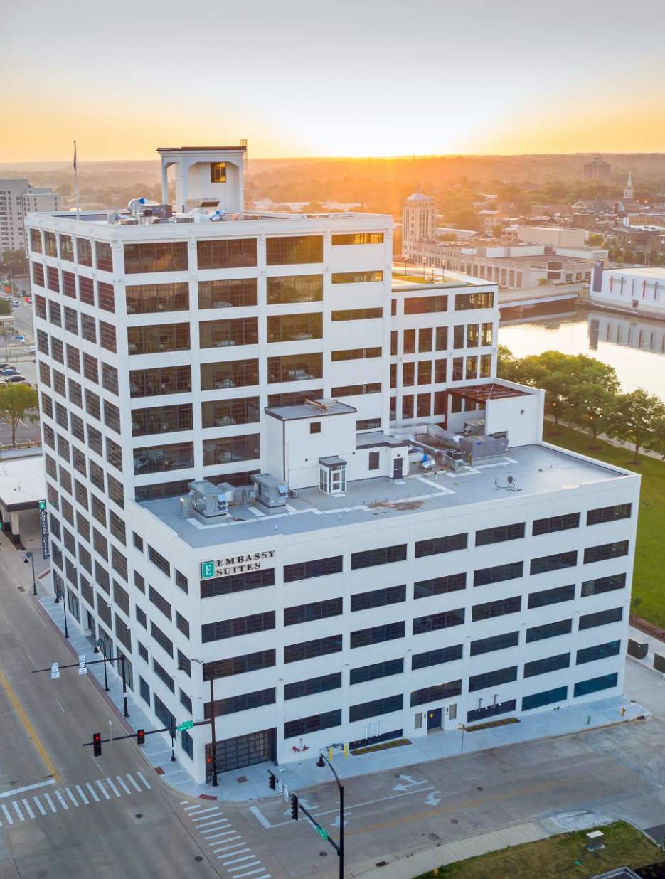 Aerial view of Embassy Suites at sunset, with city skyline and river park in Rockford, IL