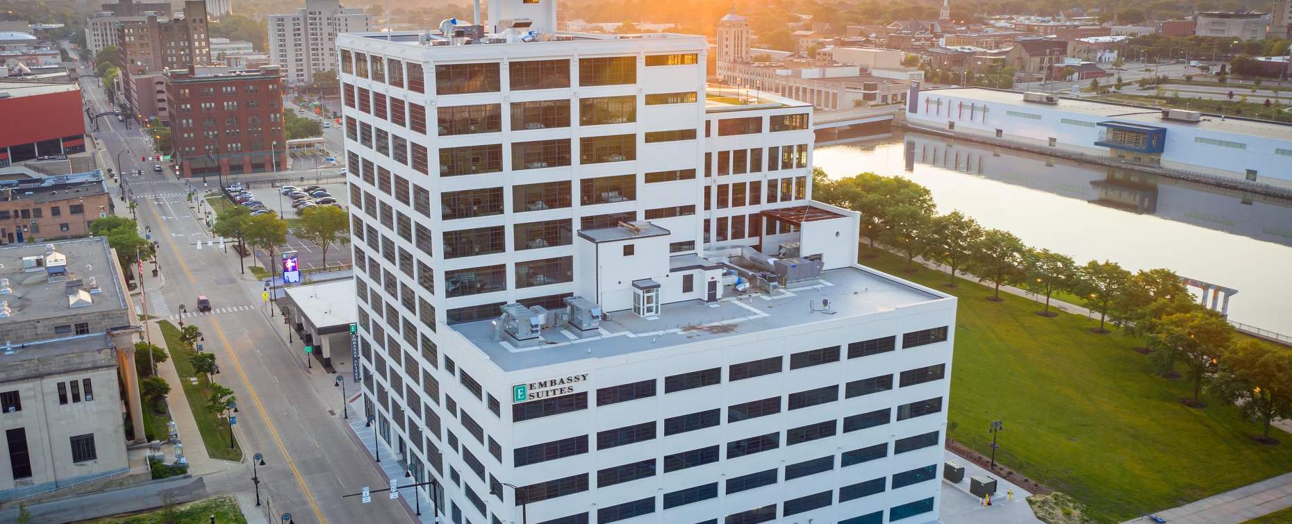 Aerial view of Embassy Suites at sunset, with city skyline and river park in Rockford, IL