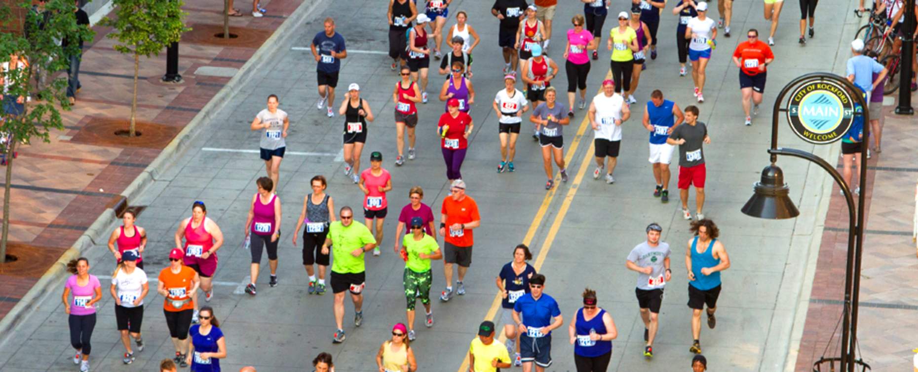 Lively community running event in Rockford with diverse participants in colorful athletic wear, joggers and walkers filling a city street.