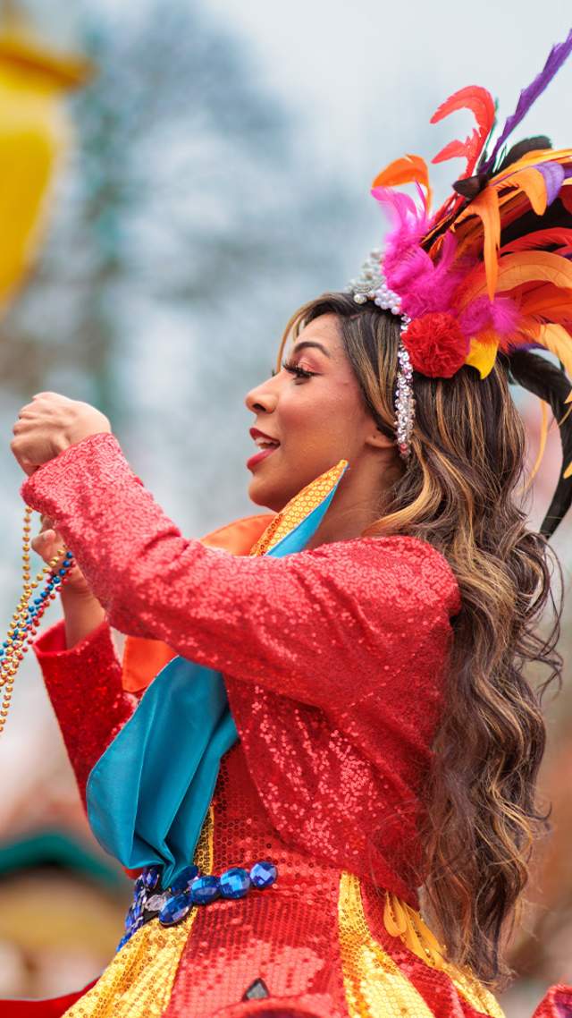 Costumed performer placing beads over girl's head at Six Flags Fiesta Texas' Mardi Gras Festival.