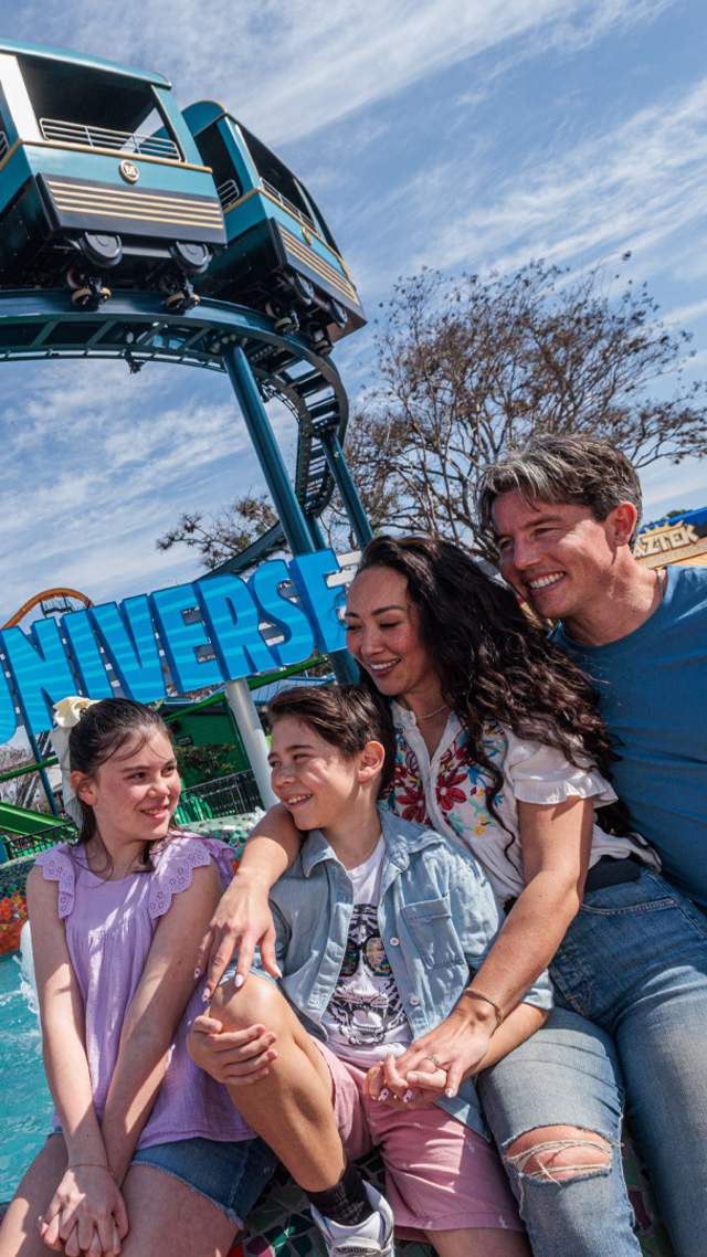 Family hugging in front of ride.