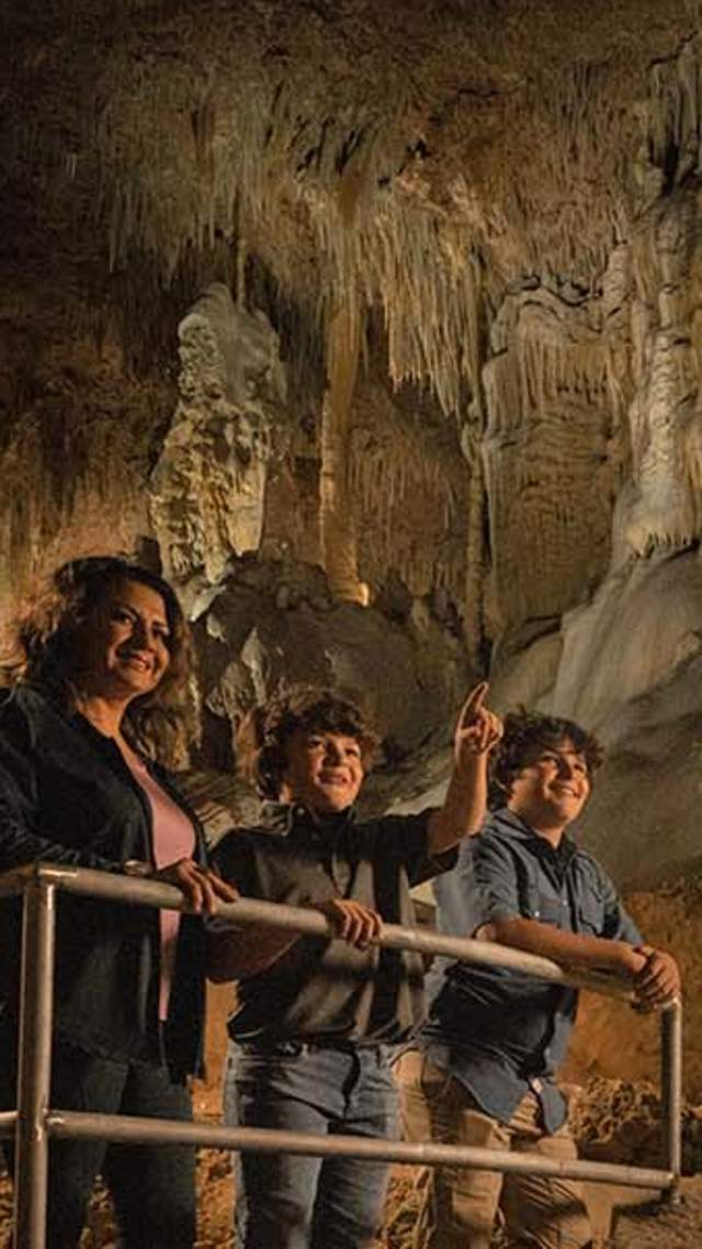 Mother and two sons exploring inside cave at Natural Bridge Caverns in San Antonio.
