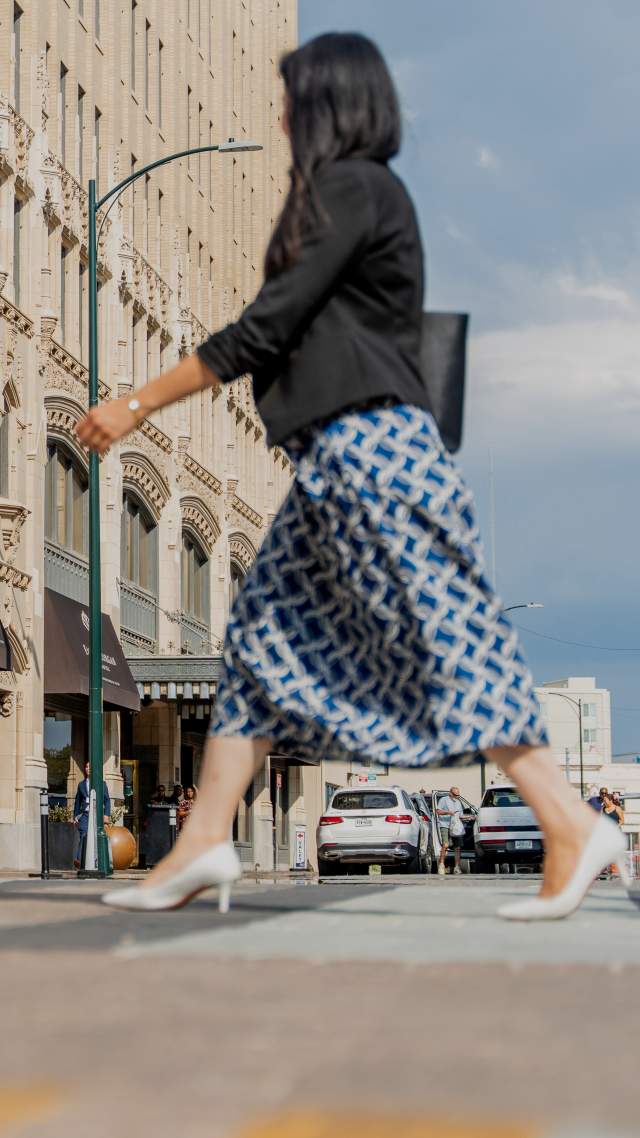 Woman in professional clothing walking in front of the Emily Morgan Hotel.