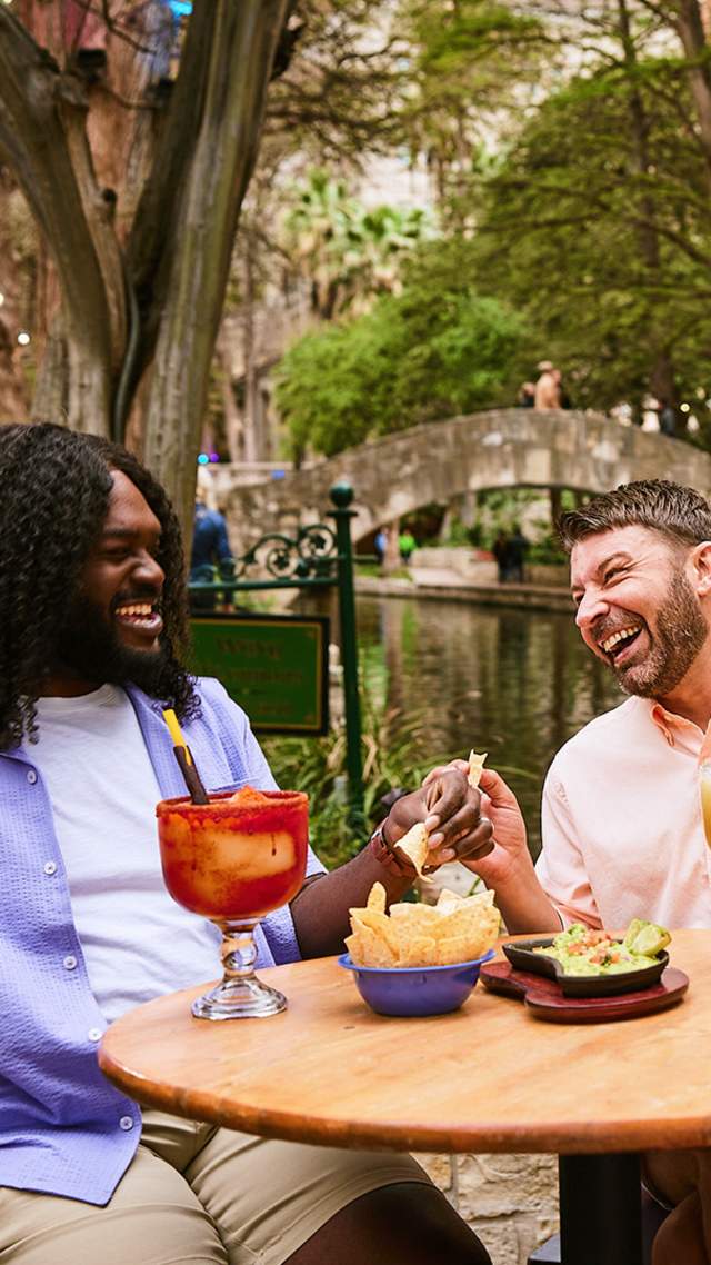Two men on the River Walk enjoying chips and margaritas