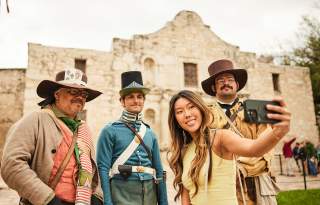 Girl taking a selfie with Alamo staff in costume