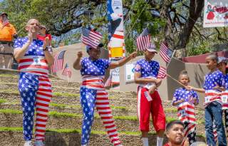 Family dressed in patriotic attire handing out flags.