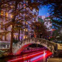 River Walk lit up with holiday lights and glow from river barge
