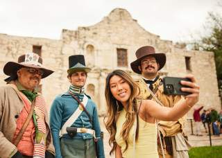 Girl taking a selfie with Alamo staff in costume
