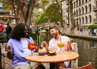 Two men on the River Walk enjoying chips and margaritas