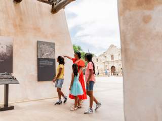 Family walking through exhibit outside of the Alamo in San Antonio, Texas.