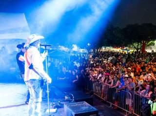 Man playing guitar and singing to crowd at Fiesta San Antonio.