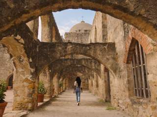 Woman walking through San Antonio Missions National Historial Park pathway