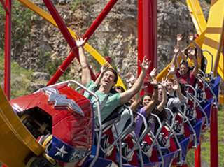 People on Wonder Woman rollercoaster with their hands in the air.