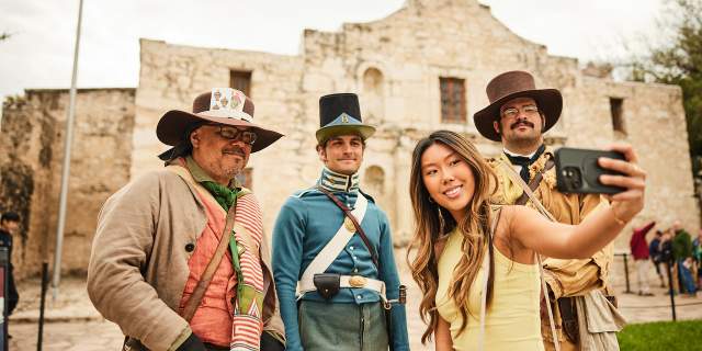 Girl taking a selfie with Alamo staff in costume