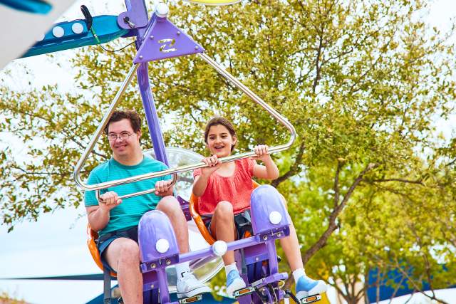 Boy and girl on air ride with trees behind them
