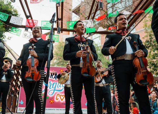 Mariachis standing in front of papel picado