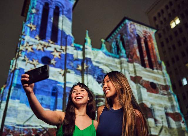 Two girls in front of light show projection