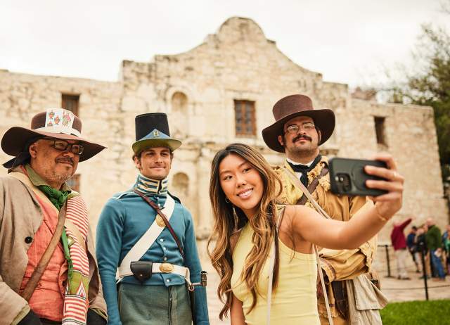 Girl taking a selfie with Alamo staff in costume